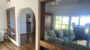 A spacious living area with a wooden floor, a green sofa, and a ceiling fan.