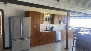 A modern kitchen with stainless steel appliances, wooden cabinets, and a tiled floor.