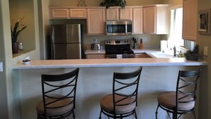 A kitchen with a central island, stainless steel appliances, and light-colored cabinets. - STEPS From the Pool! Relax in your Comfy Pool-side Condo! (Oro Valley)