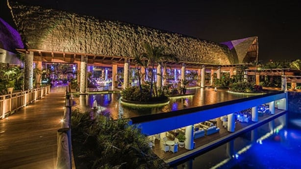 A resort with a pool area, wooden deck, and tropical plants.