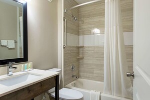 Un baño con lavamanos, espejo, ducha e inodoro.