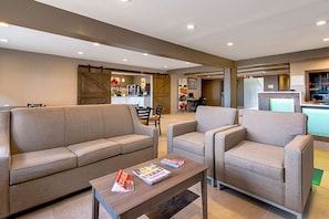 Un espacio de sala moderno con un sofá, sillones y una mesa de centro.