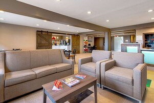 Un espacio de sala moderno con un sofá, sillones y una mesa de centro.