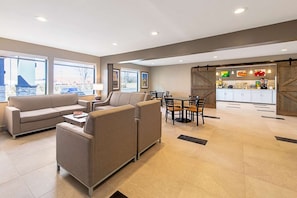 Un interior moderno con un conjunto de sofás, una mesa de comedor con sillas y una cocina con mostrador y armarios.