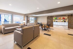 Un interior moderno con un conjunto de sofás, una mesa de comedor con sillas y una cocina con mostrador y armarios.
