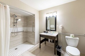 Un baño con ducha, inodoro, lavamanos y espejo.