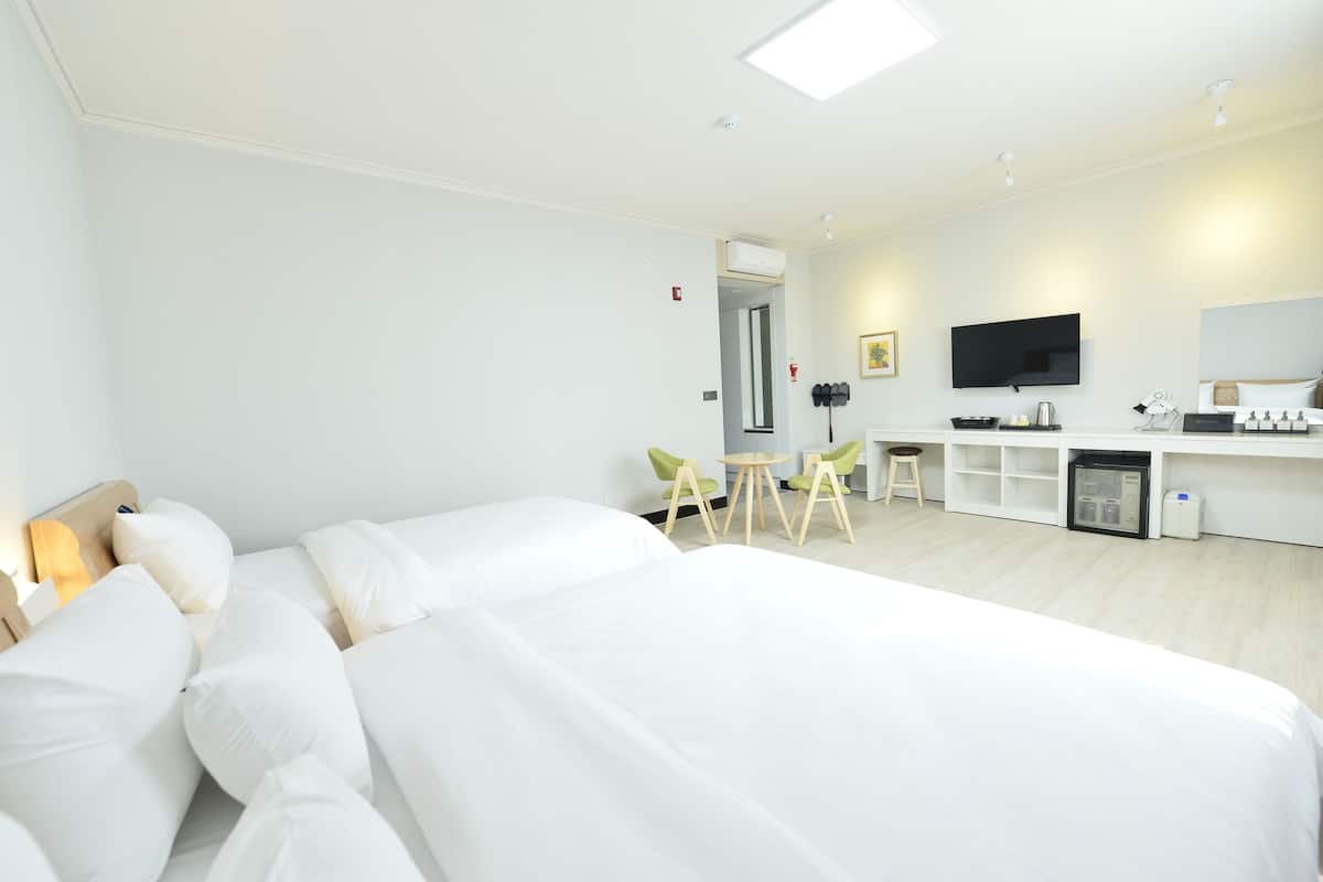 A hotel room with a large bed, a desk with a chair, a television, and a minibar.
