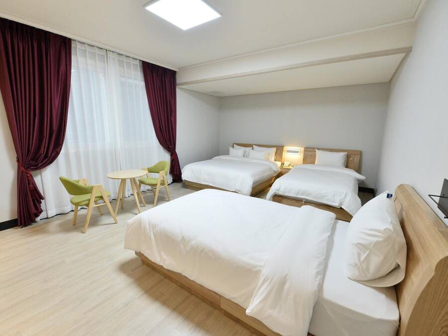 A hotel room with two beds, a small table, and a chair.
