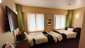 Habitación de hotel con dos camas, un escritorio, una silla, un televisor y una ventana con cortinas.