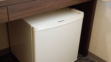 A compact white refrigerator under a wooden cabinet in a room with patterned flooring.