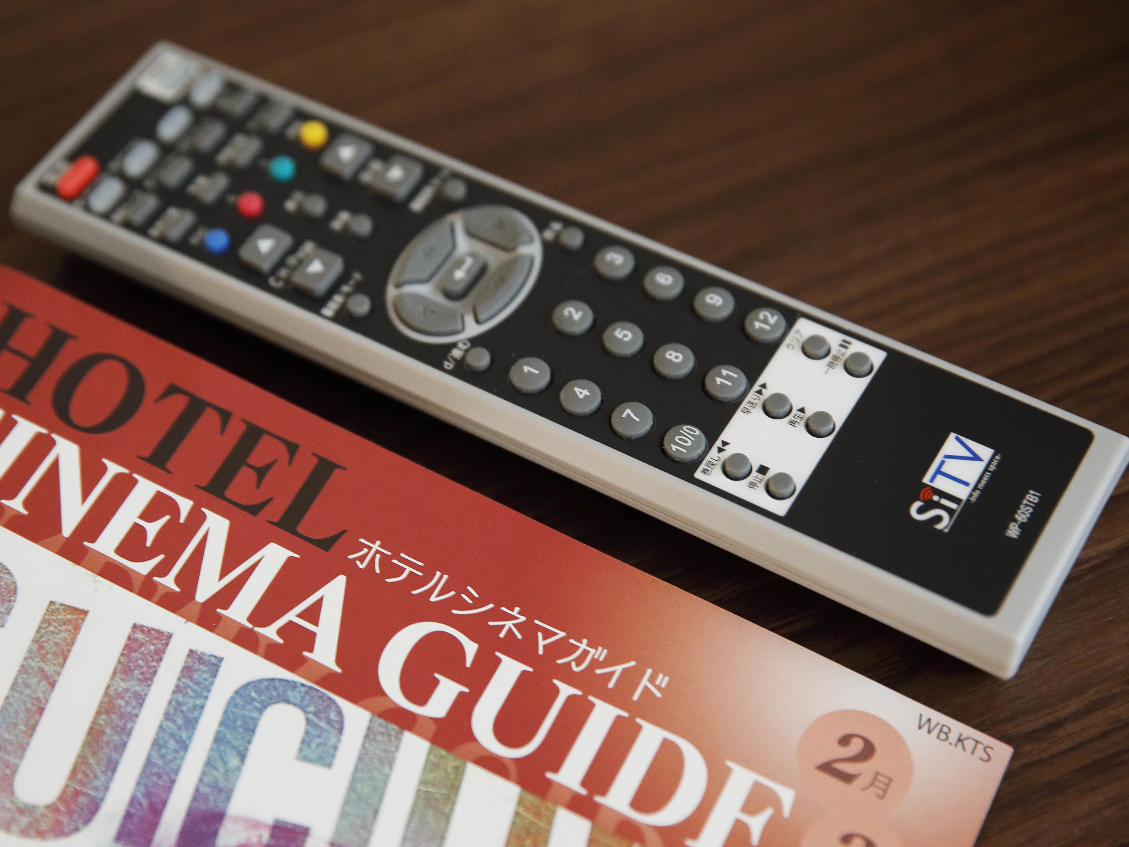 A remote control and a hotel cinema guide.