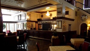 A reception area with a counter, framed pictures, and a clock on the wall. - The Mountaineer Hotel (Williamson)