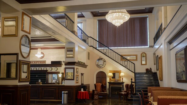 A grand lobby with a reception desk, a staircase, and a chandelier. - The Mountaineer Hotel (Williamson)