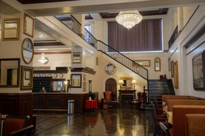 A grand lobby with a reception desk, a staircase, and a chandelier. - The Mountaineer Hotel (Williamson)