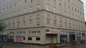 A multi-story building with a flat facade, featuring a ground-level restaurant named "Sam's Hot Dog Stand" and a hotel named "Hotel Mountainview" on the right. - The Mountaineer Hotel (Williamson)