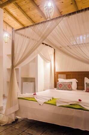 A bedroom with a canopy bed, wooden headboard, and bedside lamps. - OYO Pousada Castanheira De Trancoso (Porto Seguro)
