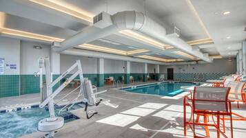Ein Schwimmbecken mit Sprungbrett, Liegestühlen und einer Decke mit Luftschlitzen.