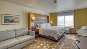 A hotel room with a bed, a sofa, a desk, a window, and a picture on the wall. - Holiday Inn Appleton by IHG (Appleton)