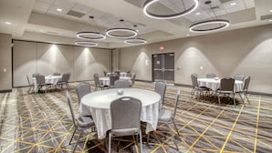 A conference room with round tables and chairs, a patterned carpet, and modern circular ceiling lights. - Holiday Inn Appleton by IHG (Appleton)
