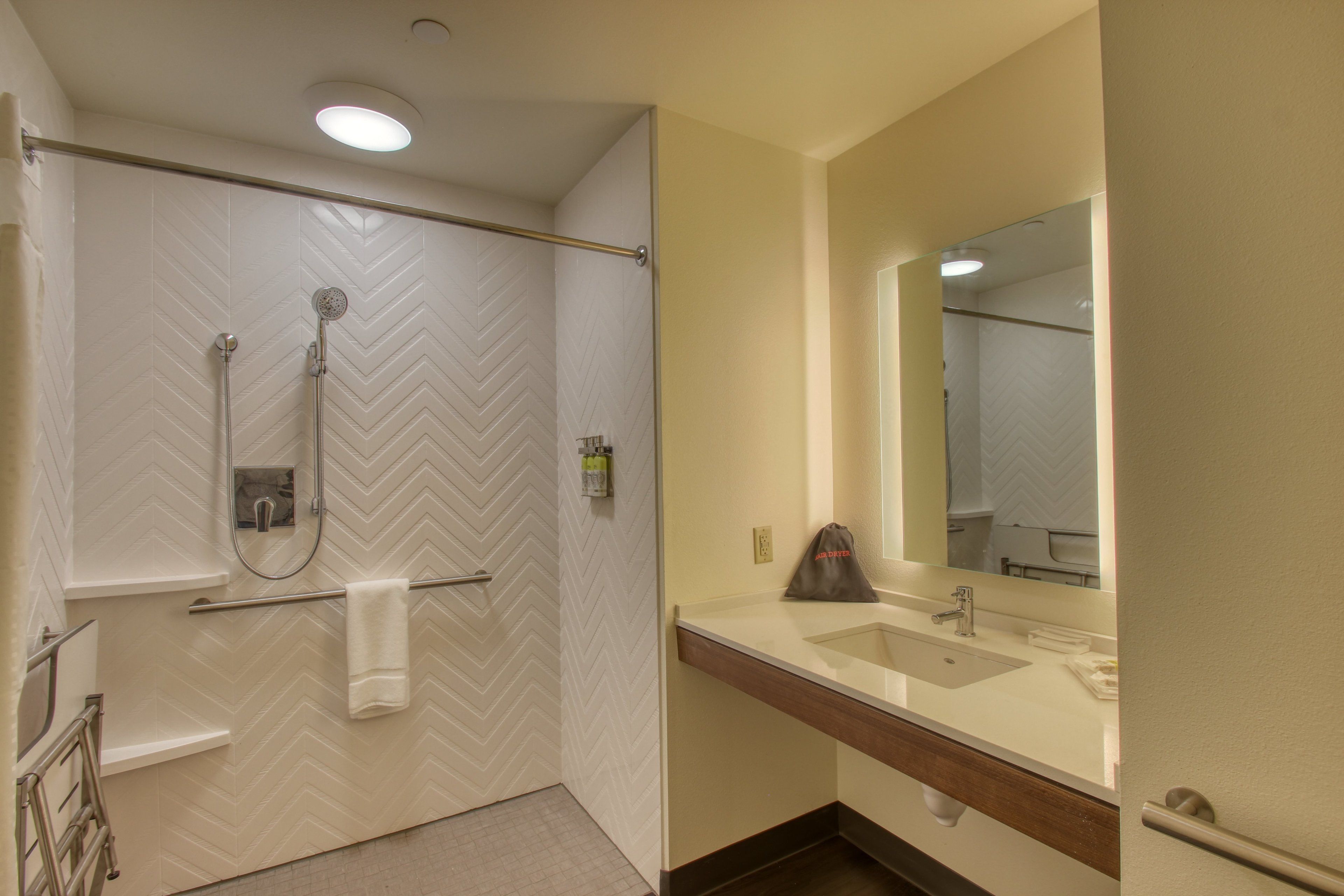 A bathroom with a shower, a sink, and a mirror.