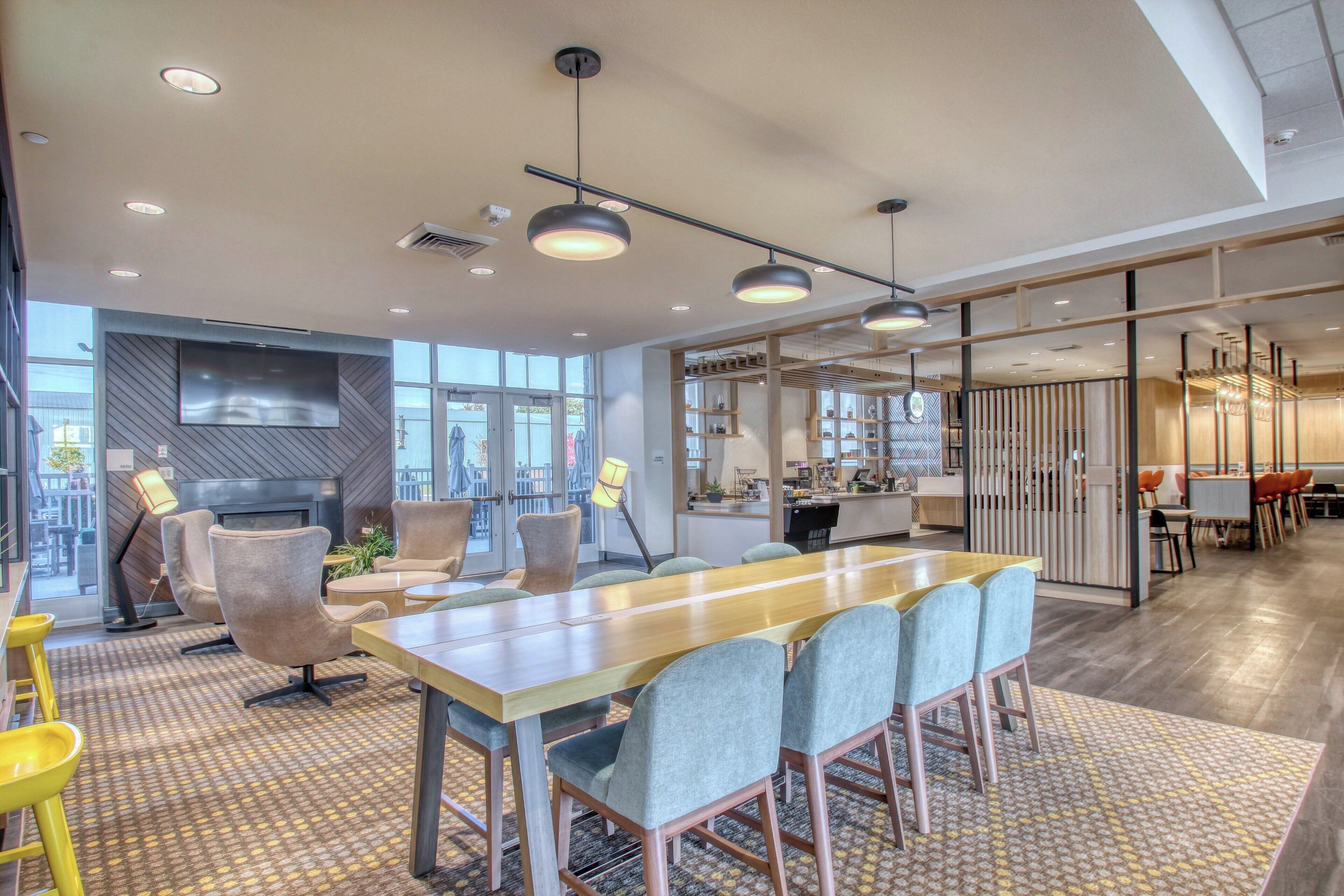 A modern office space with a long table, chairs, and a television.