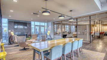 A modern office space with a long table, chairs, and a television.