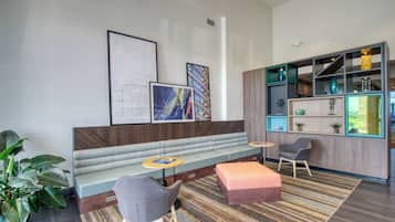 Ett modernt loungeområde med en soffa, stolar, ett litet bord och en bokhylla.