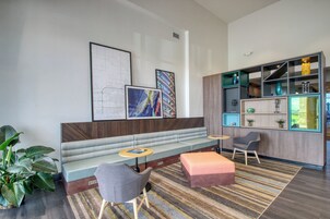 Un espacio lounge moderno con sofá, sillas, una mesita y una estantería.
