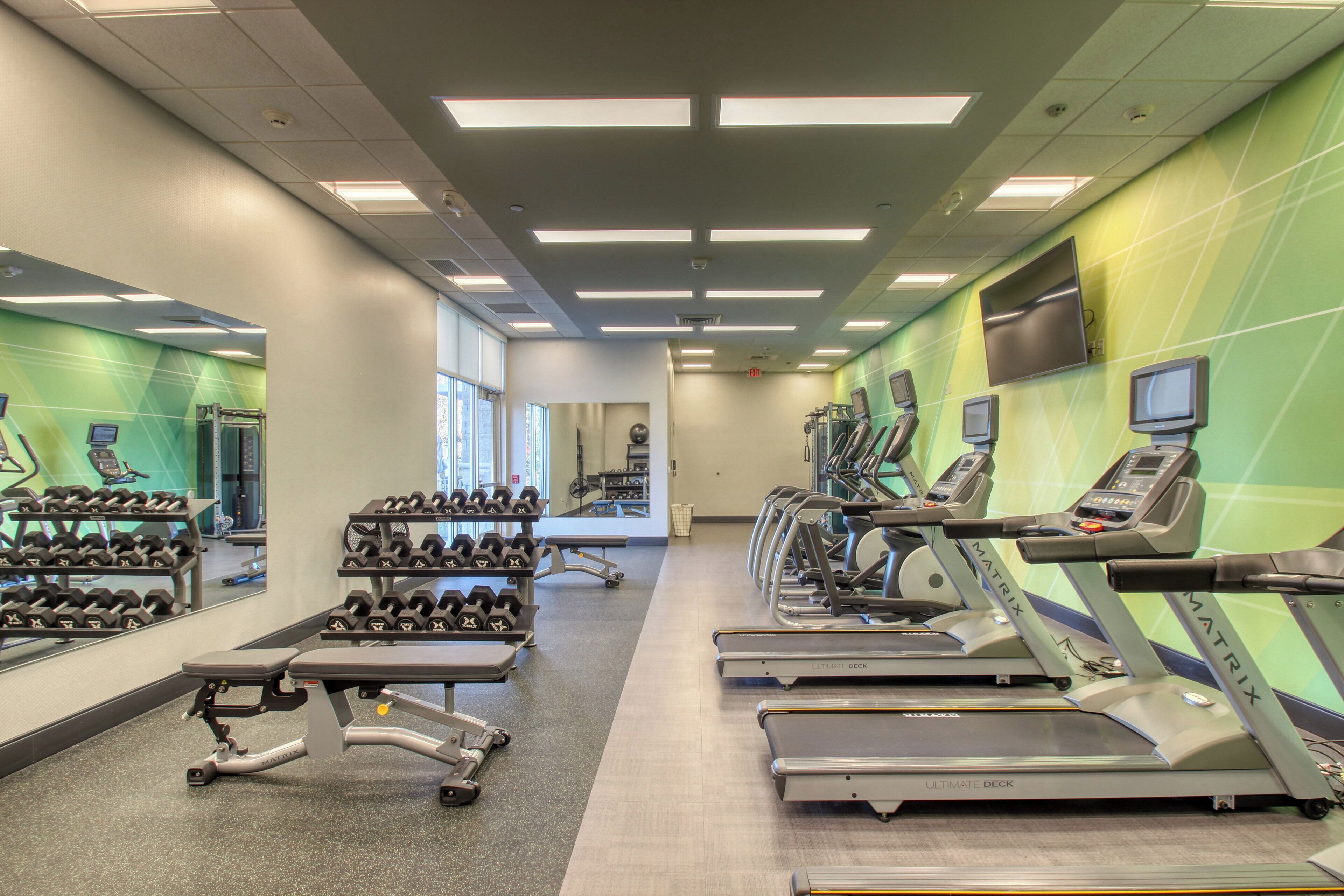Ein Fitnessstudio mit Laufbändern, Kurzhanteln und Trainingsgeräten.