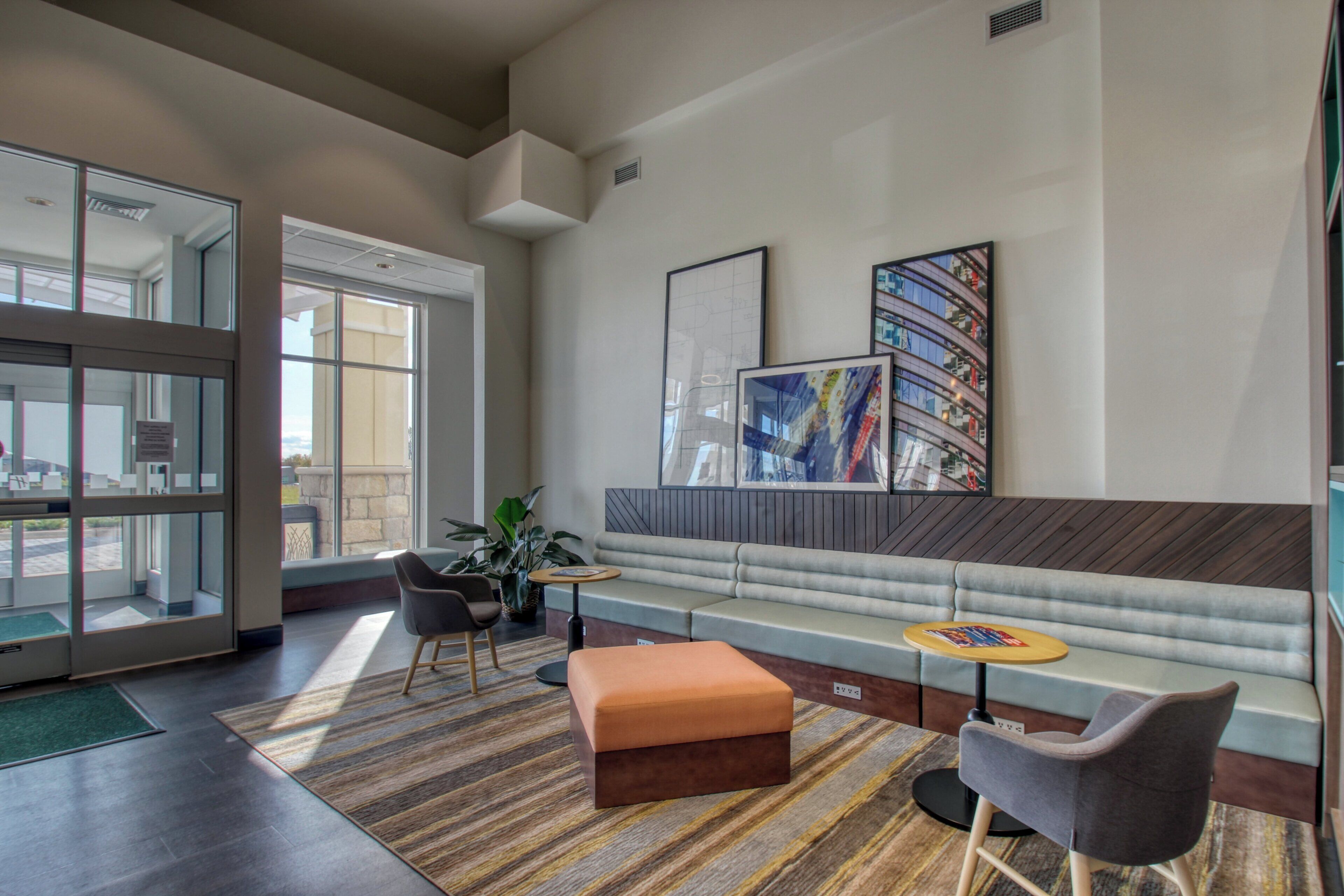 A modern lobby with a seating area, a reception desk, and a large window offering a view of the outside.