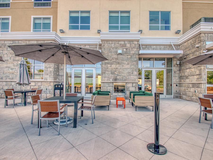 An outdoor patio area with tables and chairs, umbrellas, and a stone building facade.