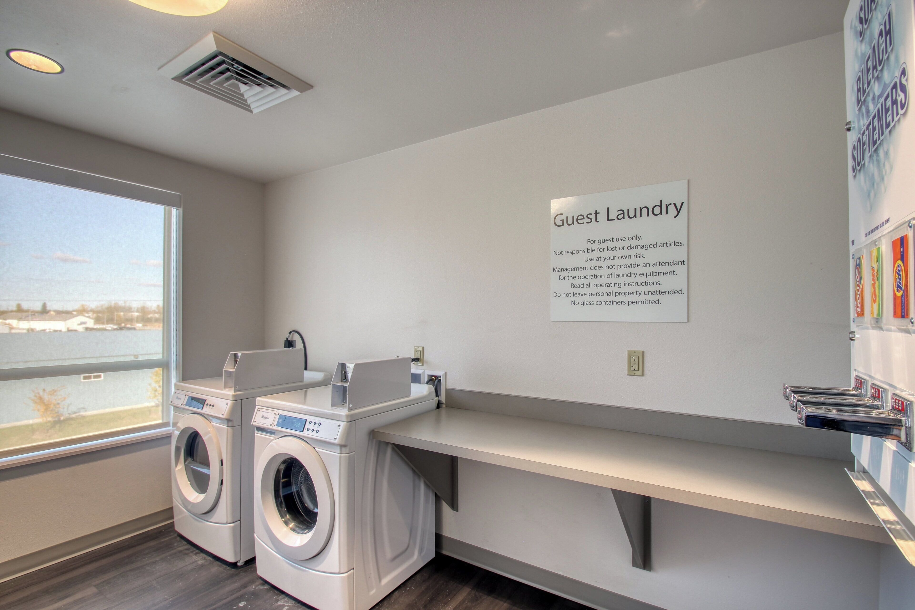 A guest laundry area with two front-loading washing machines, a sink, and a sign with laundry instructions.