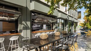 Un espace bar extérieur avec une longue table, plusieurs chaises et un comptoir avec des tabourets.