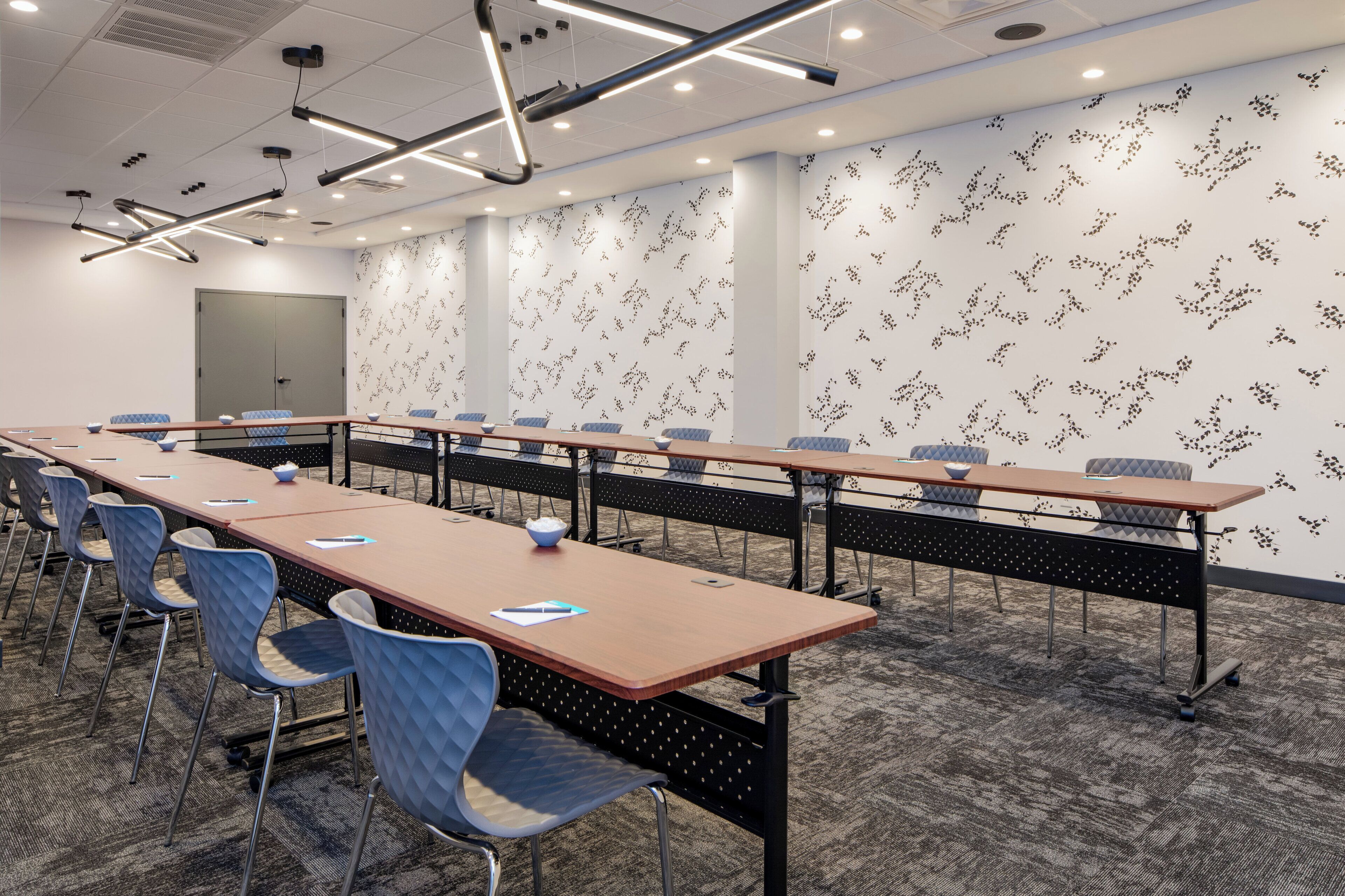 A conference room with a long table, chairs, and a patterned wall.