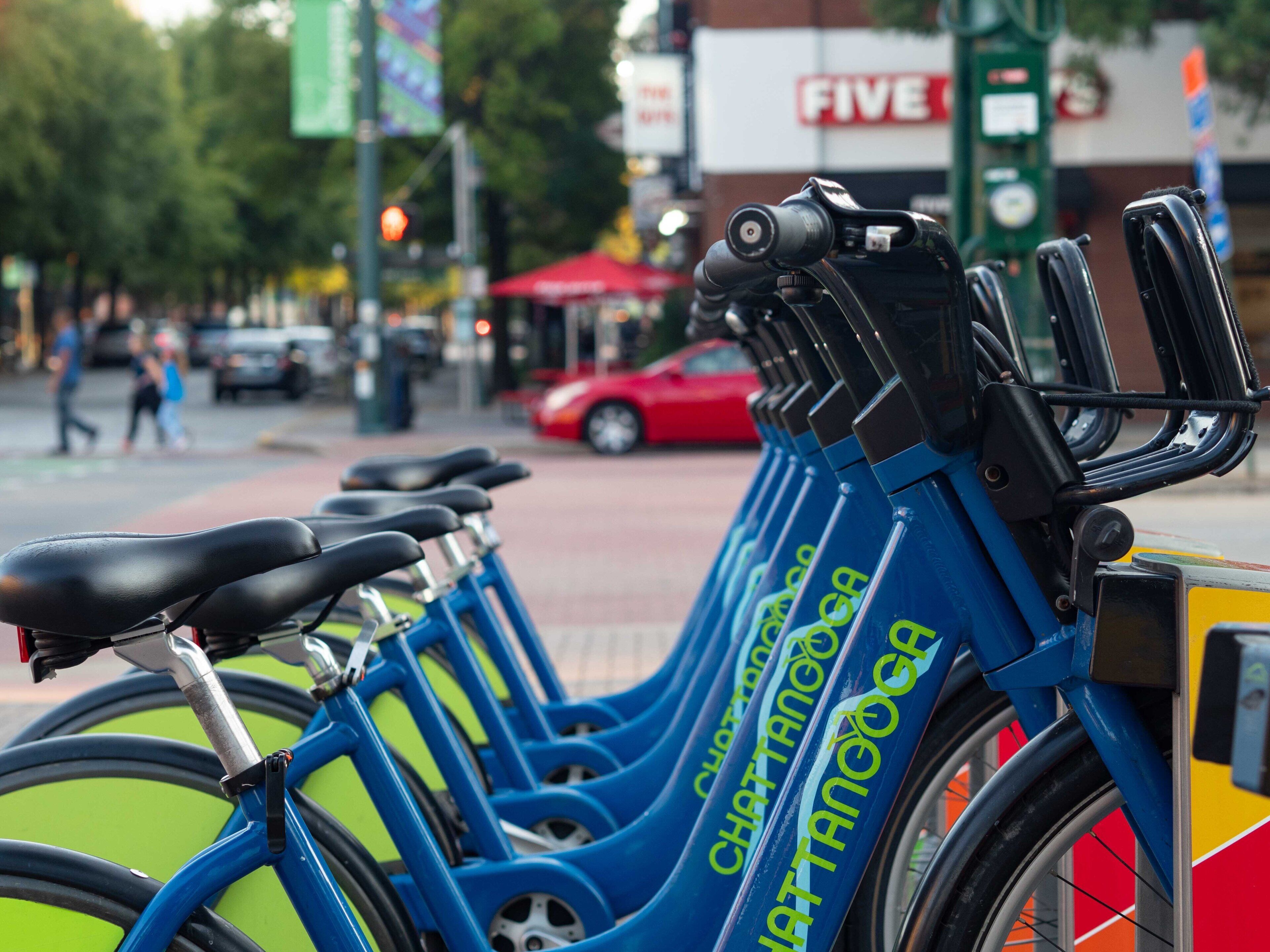 Een rij blauwe fietsen met 'Chattanooga'-logo, geparkeerd op een straat.