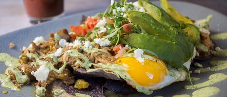 A plate of food with an egg, avocado, and greens.