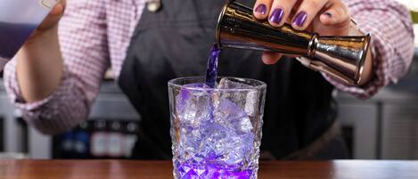 Una persona vertiendo un líquido morado en un vaso con cubitos de hielo.