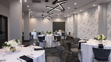 A conference room with round tables, chairs, and modern lighting fixtures.