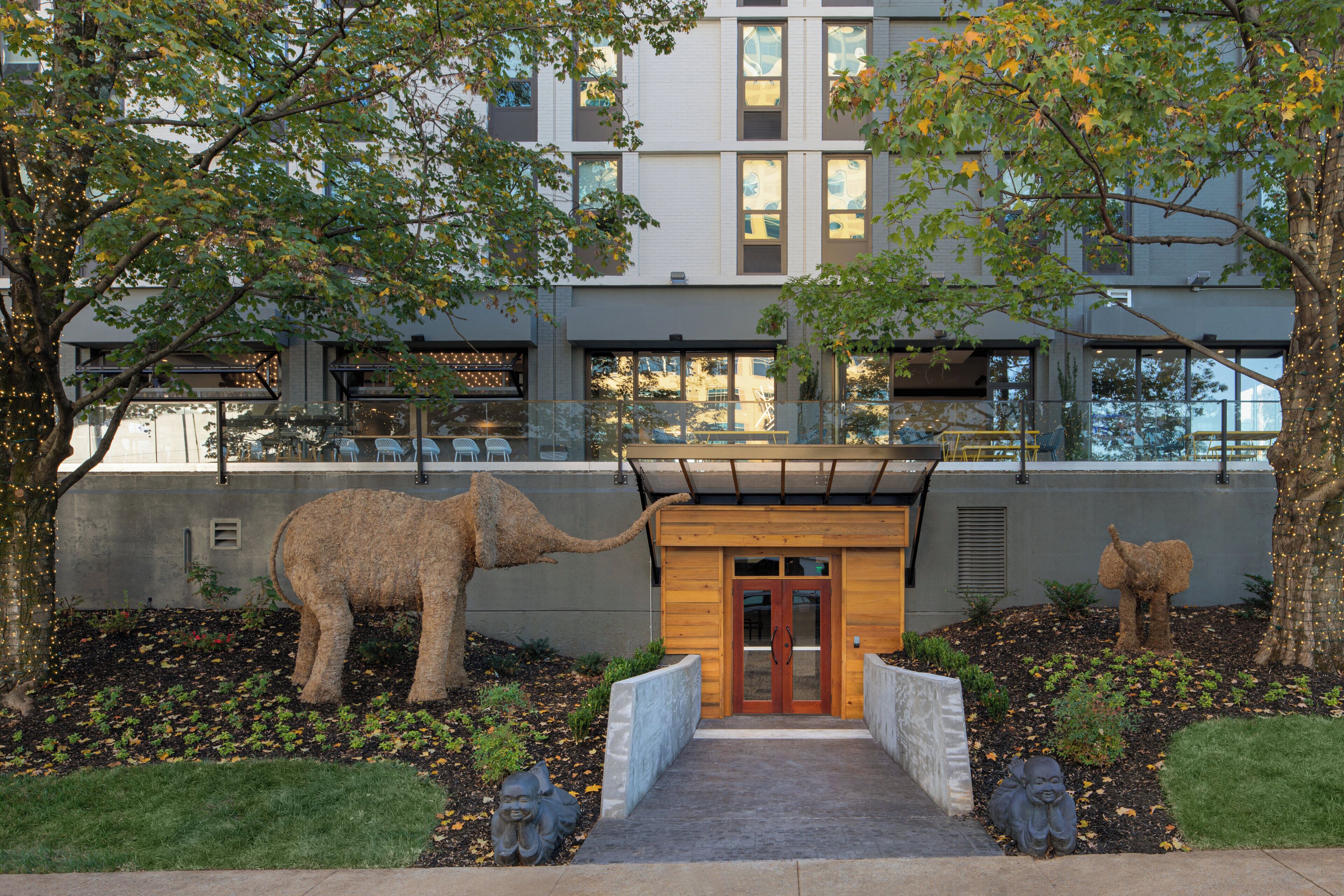 A building with a modern architectural style, featuring a central entrance with a wooden door and a covered walkway.