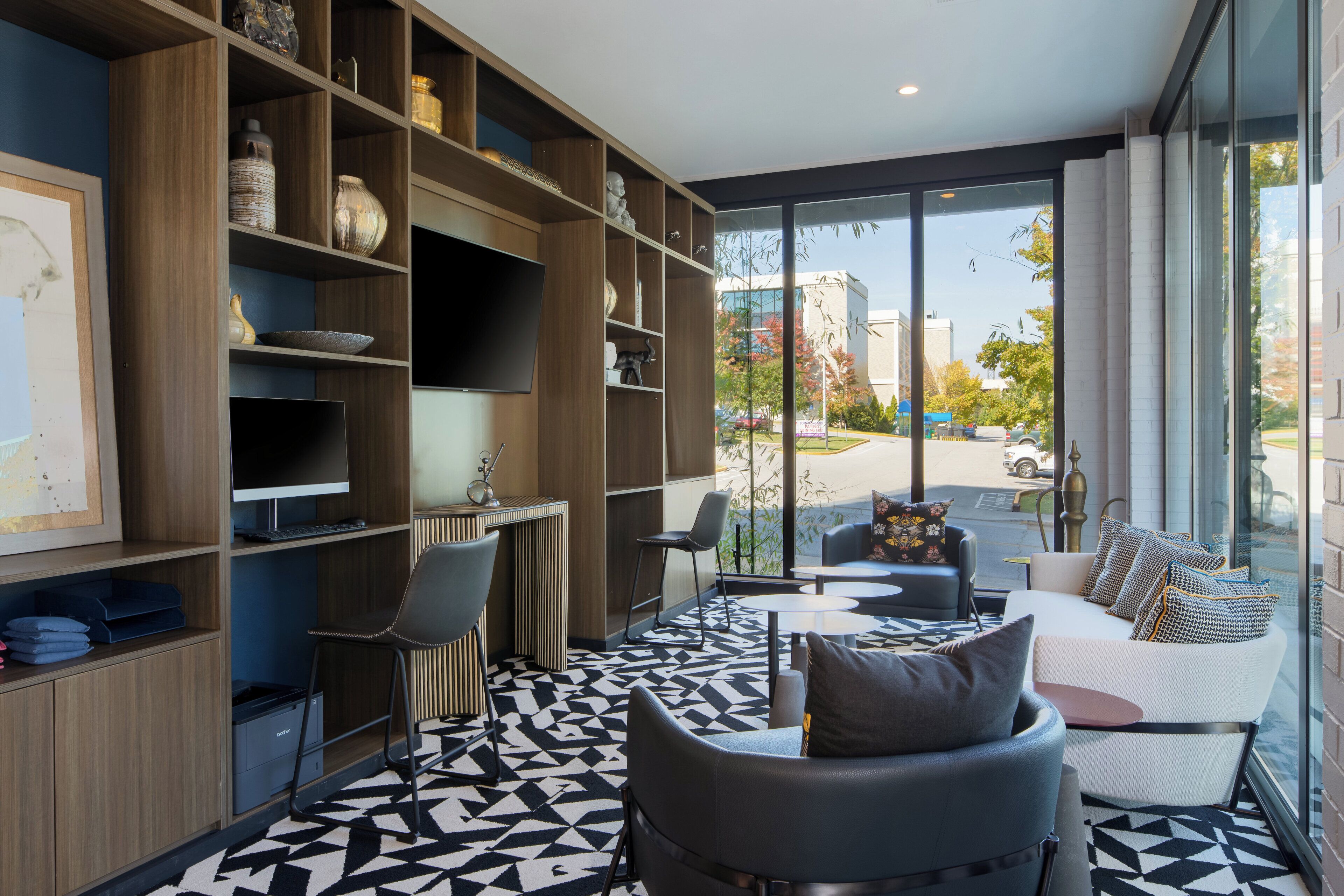 Un espacio habitable moderno con un ventanal grande, un sofá, una mesa de centro y un escritorio con un ordenador.