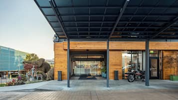 A modern building entrance with a covered walkway, glass doors, and a motorcycle parked outside.