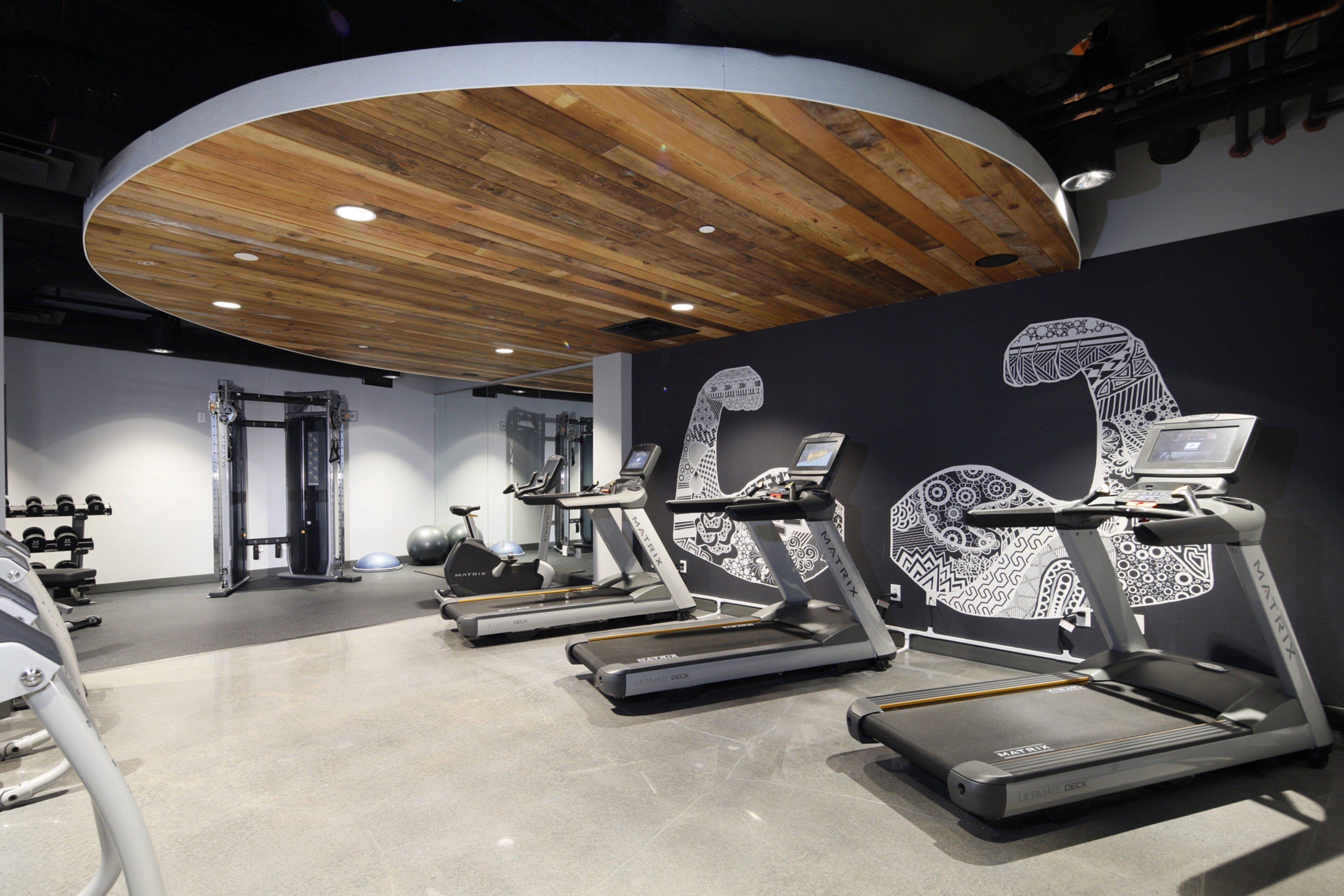 A gym with treadmills, weight machines, and a wooden ceiling.