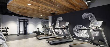 A gym with treadmills, weight machines, and a wooden ceiling.