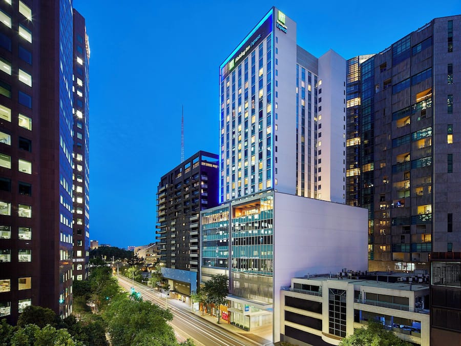 Un hotel moderno con varios pisos, ventanas amplias y un letrero llamativo.