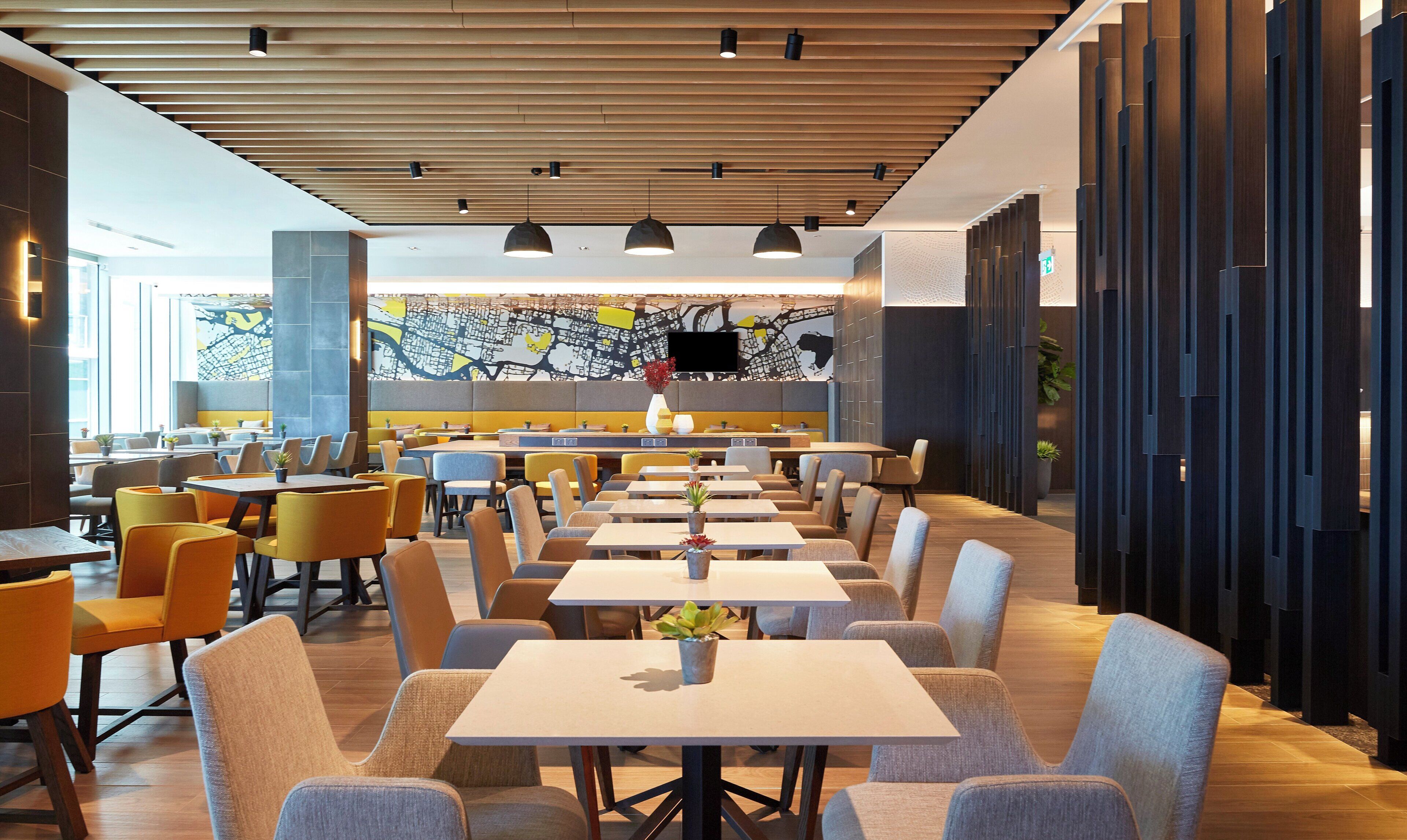 Um restaurante moderno com um balcão extenso, várias mesas e cadeiras.