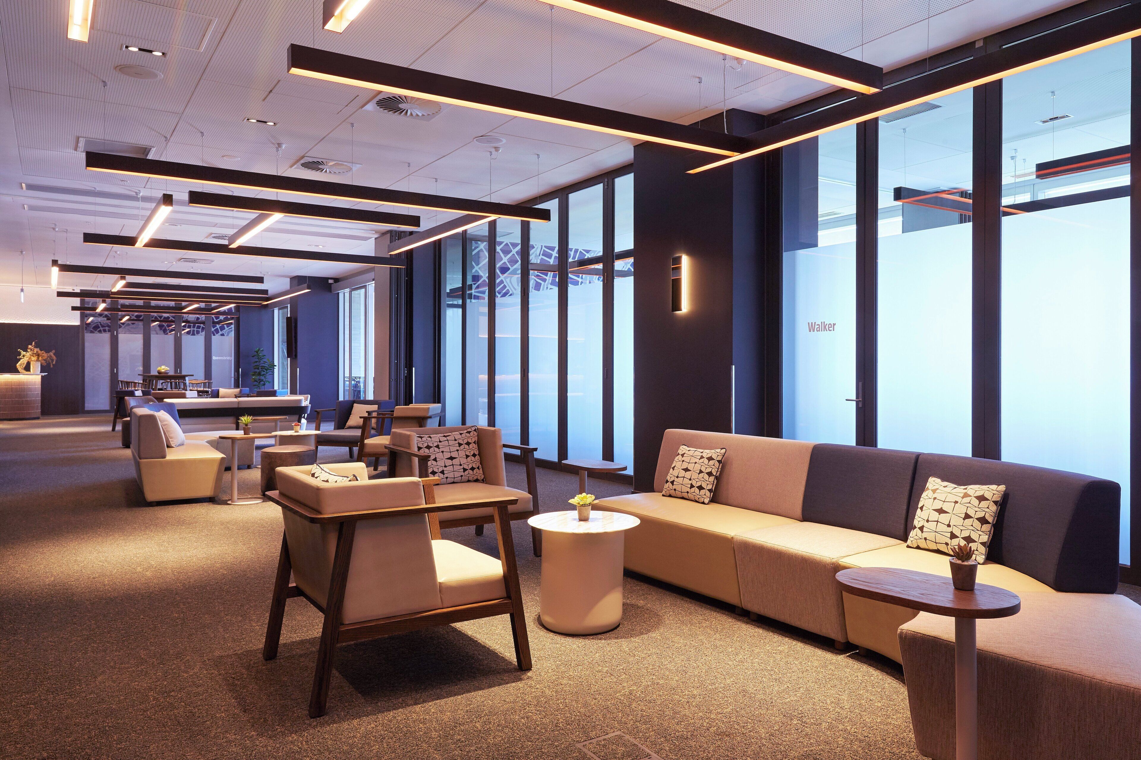 A modern lounge area with seating, tables, and large windows.