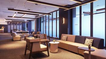 A modern lounge area with seating, tables, and large windows.