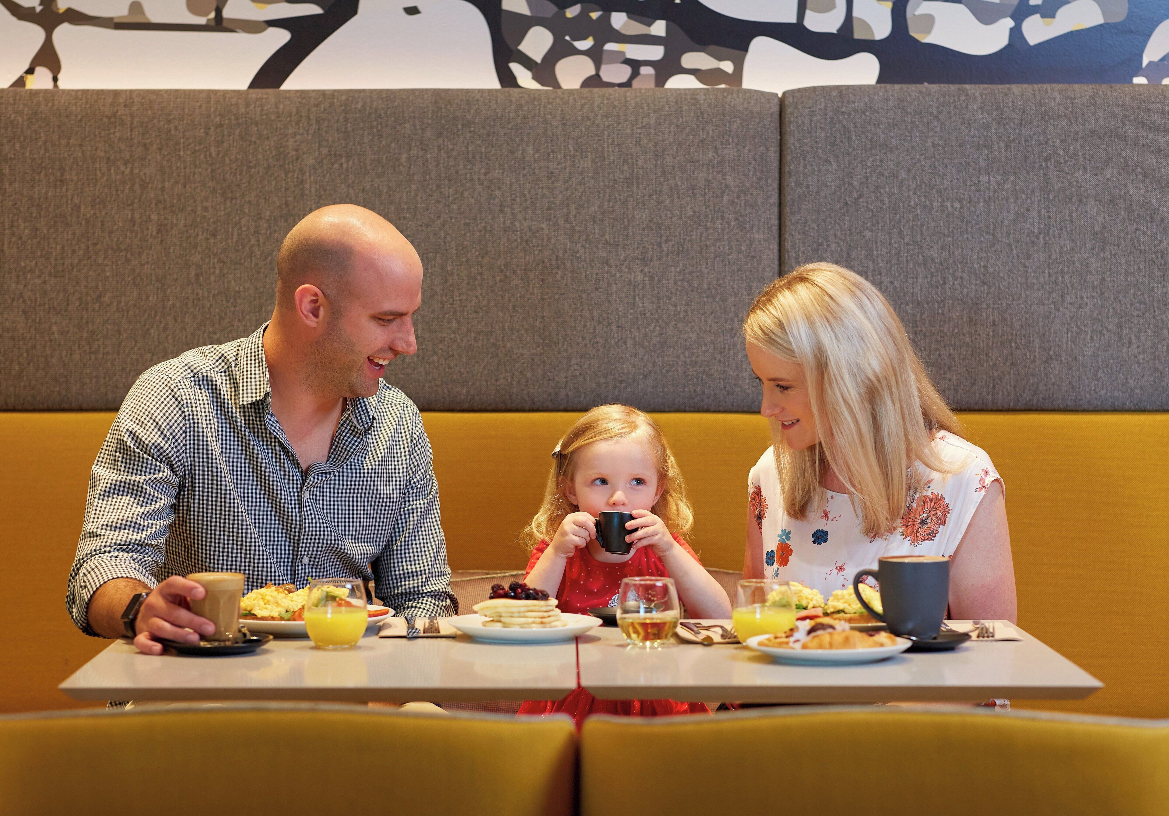 A family dining at a table with a sofa in the background.
