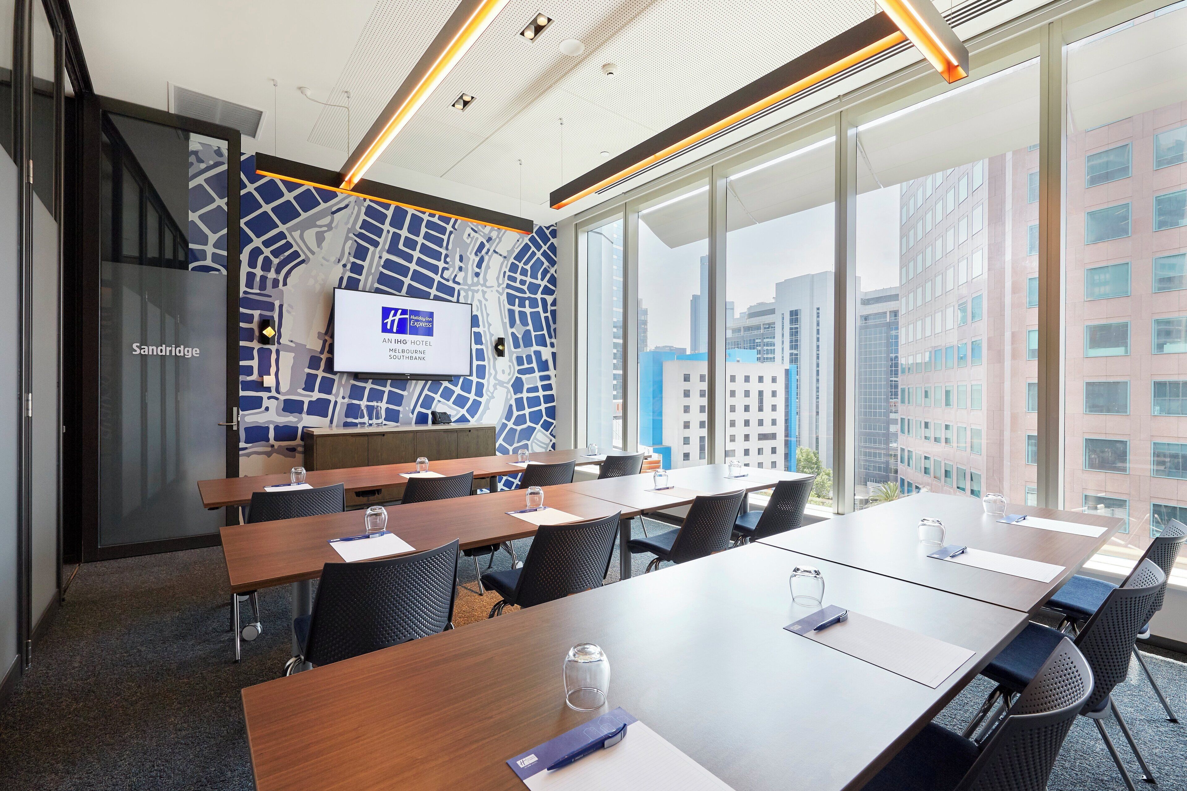 A conference room with a city view, a map on the wall, and a Holiday Inn Express sign.