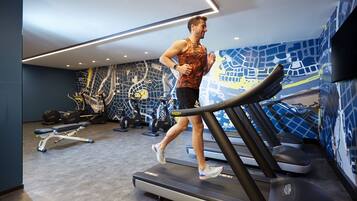 Une salle de sport équipée de tapis de course, de poids et d’autres appareils d’exercice.